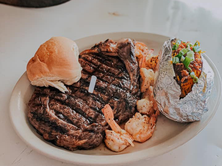Ribeye Steak with shrimp, a Baked Potato, and a Roll on the side